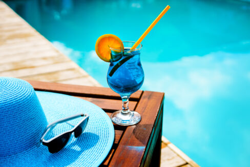 Summer,Hat,,A,Cocktail,And,Sunglasses,Near,The,Luxurious,Pool