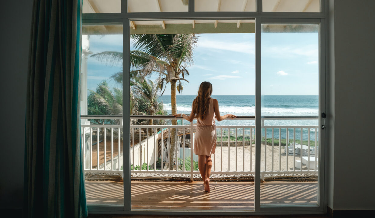 Young,Woman,Standing,On,The,Balcony,And,Looking,At,The